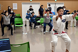写真：金丸雄介さんと受講者の皆さんがスクワットをする様子