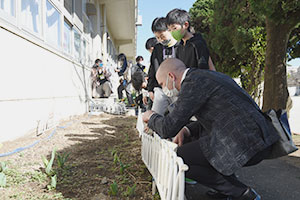 写真：チューリップの花壇を見る講師と子ども