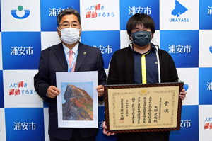 写真：内閣総理大臣賞の賞状を持った矢野さんと市長