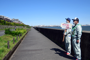 写真：看板を持って立ち入り禁止を呼び掛ける職員