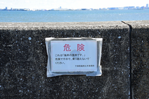 写真：護岸乗り越え禁止を呼び掛ける看板