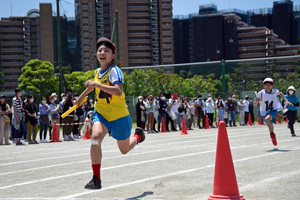 写真：選抜リレーを走る高学年の児童