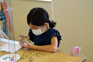 写真：真剣な表情で風鈴に絵付けをしている様子