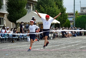 写真：1位でゴールし両手を上げる児童
