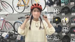 写真：自転車用のヘルメットをかぶるリポーター