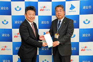 写真：寄附を贈呈する株式会社ワイズマート代表取締役と、寄附を受け取る市長の様子
