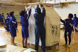 写真：体育館で仮設トイレを組み立てる生徒らと市職員