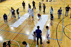 写真：体育館に護岸を転写した紙を広げる人たち