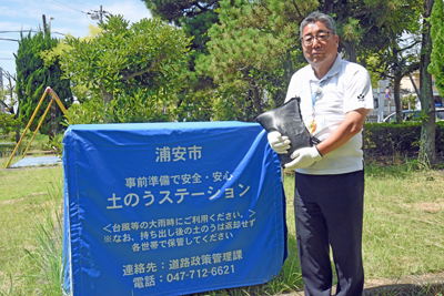 写真：土のうステーションと土のうを抱える市長