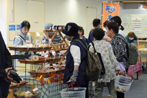 写真：陳列された手芸品やパンを見る買い物客