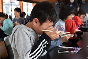 写真：おいしそうにみそ汁を食べる児童