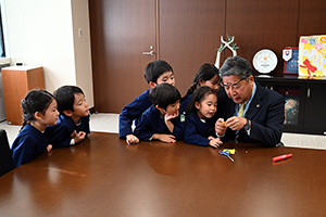 写真：市長と園児が楽しく折り紙を折る様子