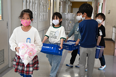 写真：牛乳やご飯を配膳室から運ぶ様子