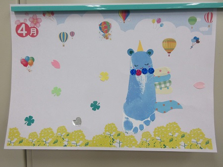 制作したカードのイメージ写真。青色の足形にユニコーンの角や耳、尻尾の飾りを付け、まわりには花の飾りと「4月」の文字が入っています。