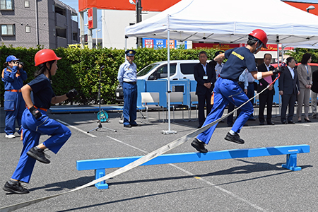 写真：ホースを持って平均台を走る様子
