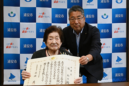 写真：お祝い状を持つ橘さんと内田市長
