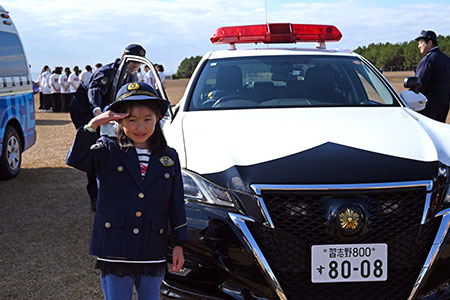 写真：警察官の制服を着た子どもとパトカー