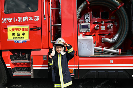 子ども用防火衣を着装してポンプ車両の前で記念撮影している様子