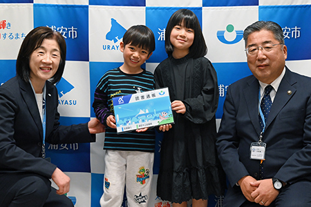 写真：読書通帳をもった子どもたちと市長、教育長