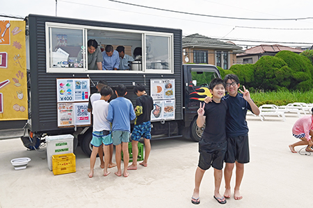 写真：キッチンカーの前でポーズをとる子供